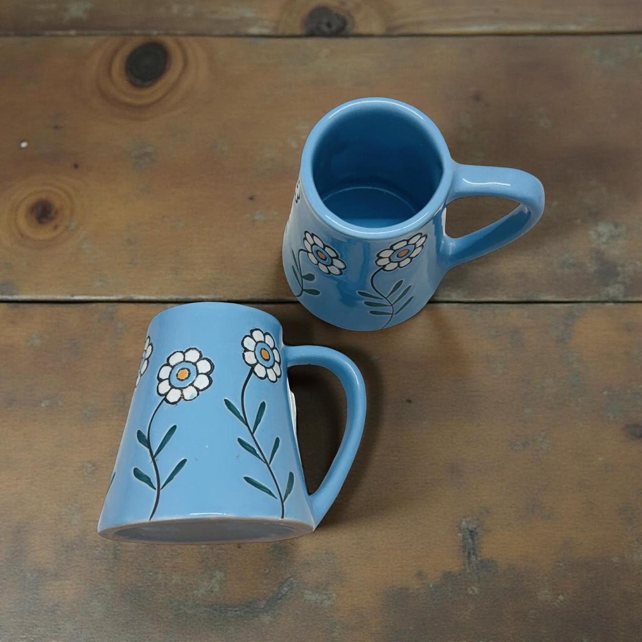 Two blue mugs with floral designs on a wooden surface