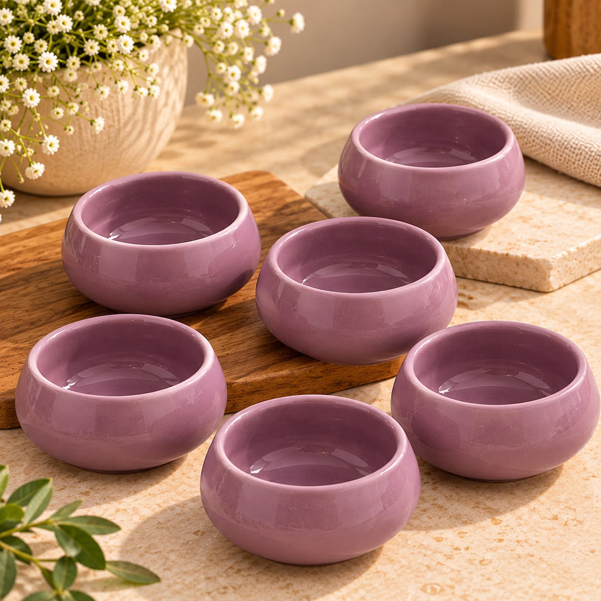Glossy pink ceramic condiment bowls arranged with colourful vegetarian dips and spreads for party snacks and appetizer serving.