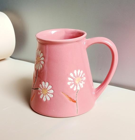 Pink mug with floral designs on a light surface
