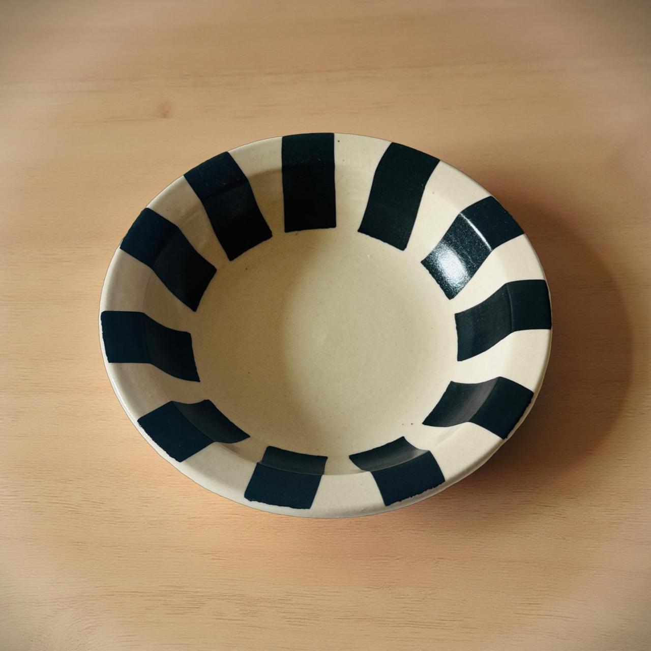 Ceramic bowl with black stripe design on a wooden surface