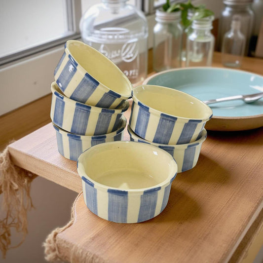 Set of ceramic bowls with blue and white stripes on a wooden surface.