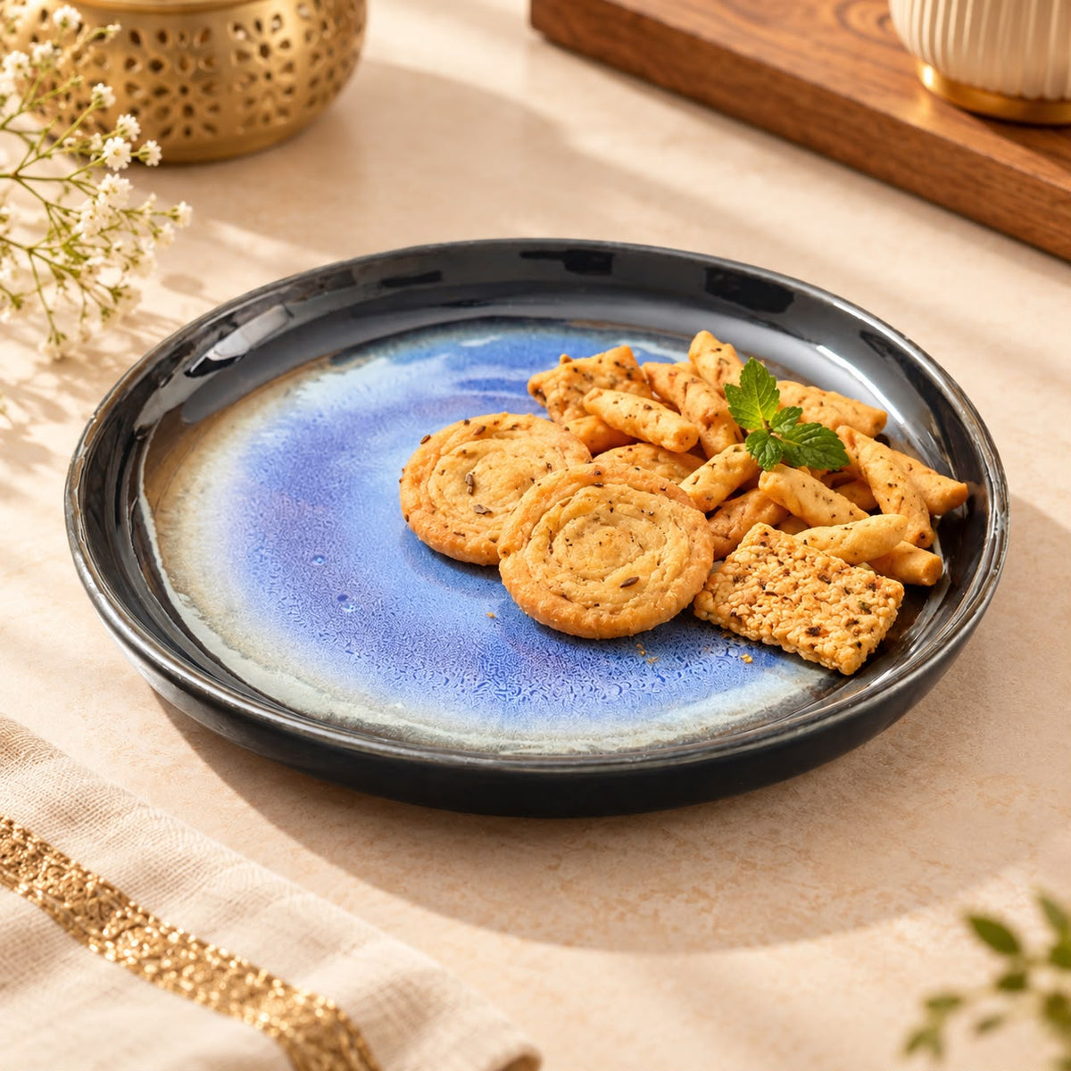 Blue glazed ceramic snack plate with a dark rim for serving Indian namkeen and biscuits.