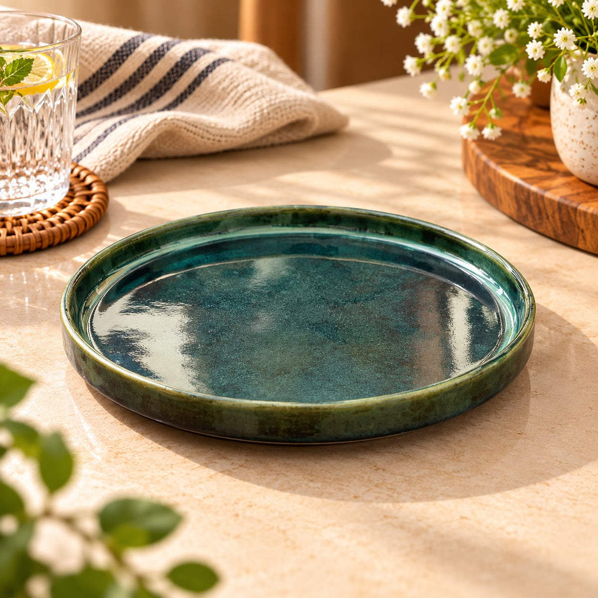 Round teal green ceramic plate styled with natural wood and cream linen for modern dining