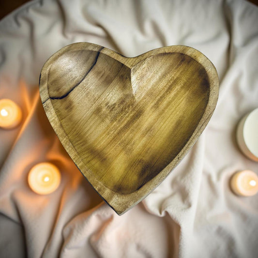 Wooden heart-shaped plate on a soft fabric background with candles