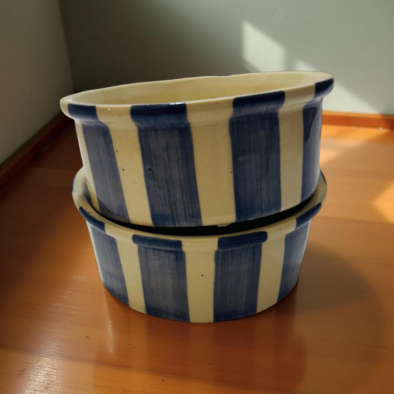 Two ceramic pots with blue and white striped design on a wooden surface.