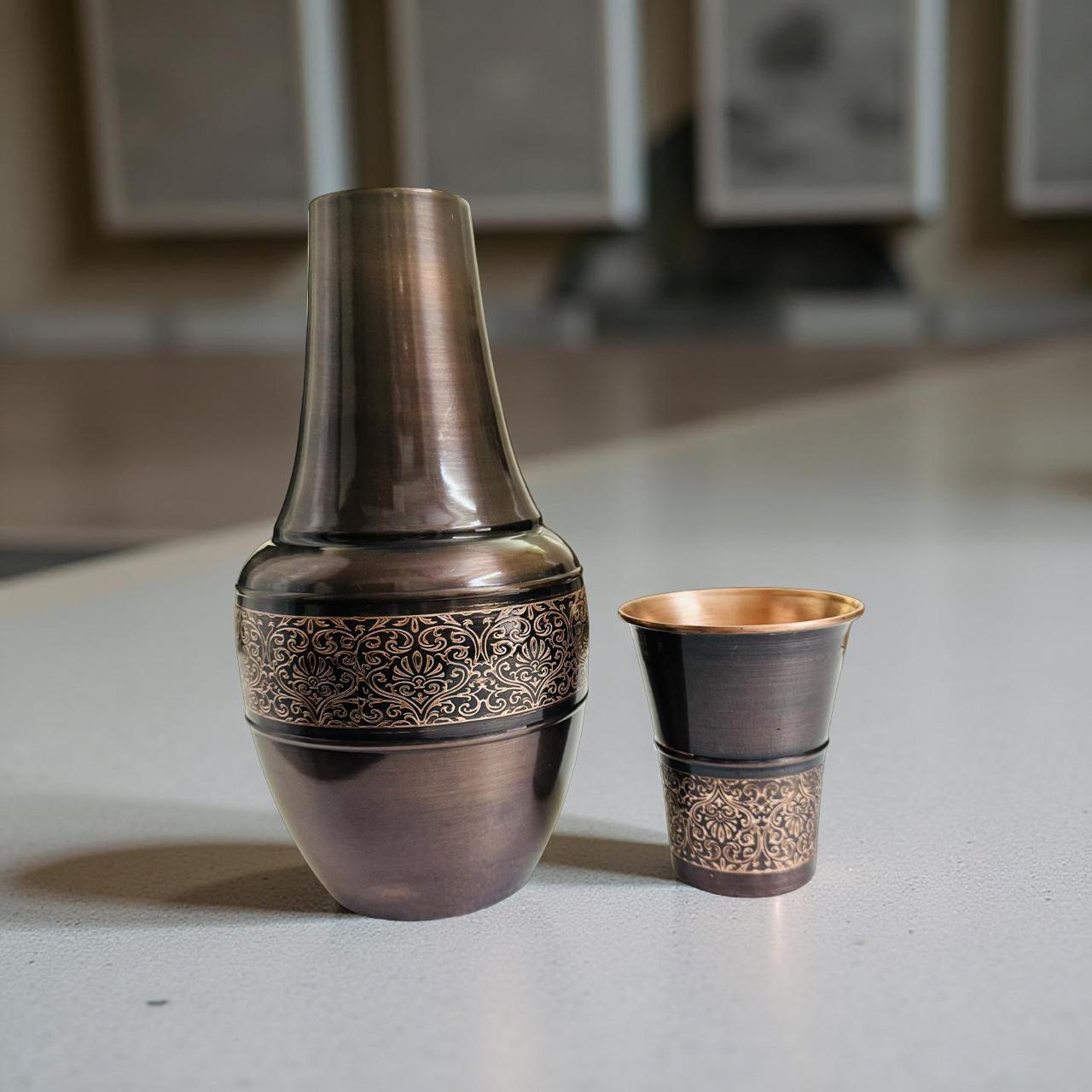 Bronze bedroom water jug and cup with intricate designs on a reflective surface.