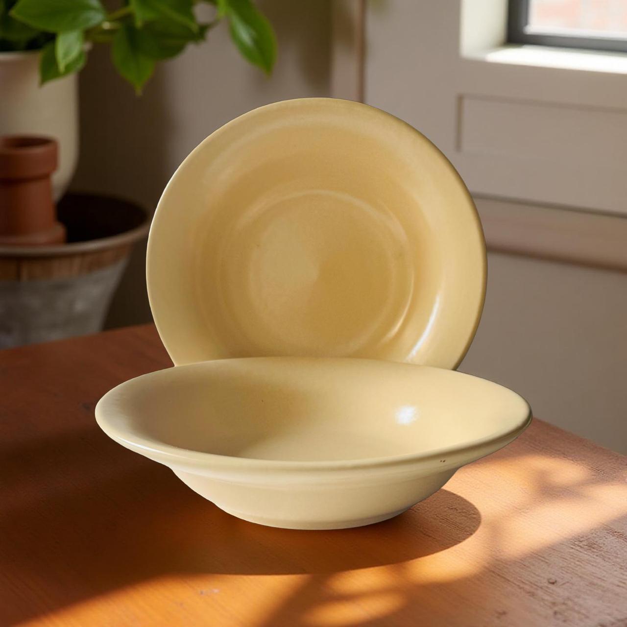 Two beige ceramic bowls on a wooden surface with a blurred indoor background