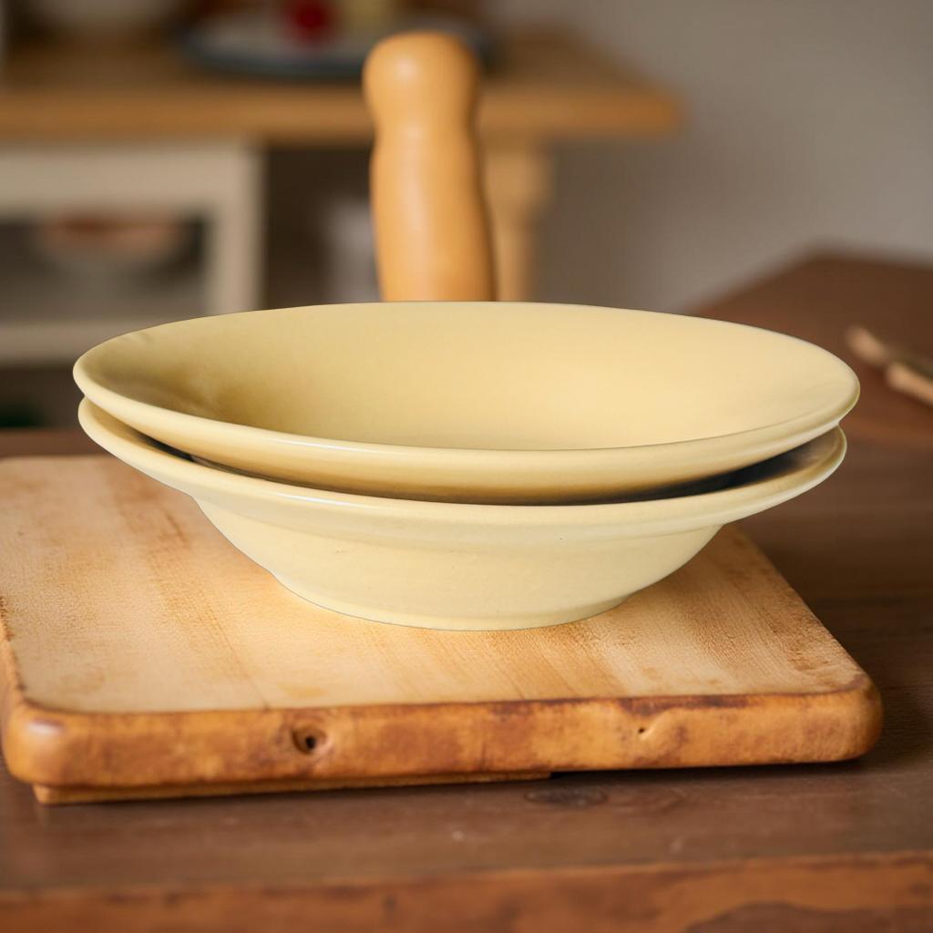 Two beige ceramic bowls stacked on a wooden cutting board with a blurred kitchen background.