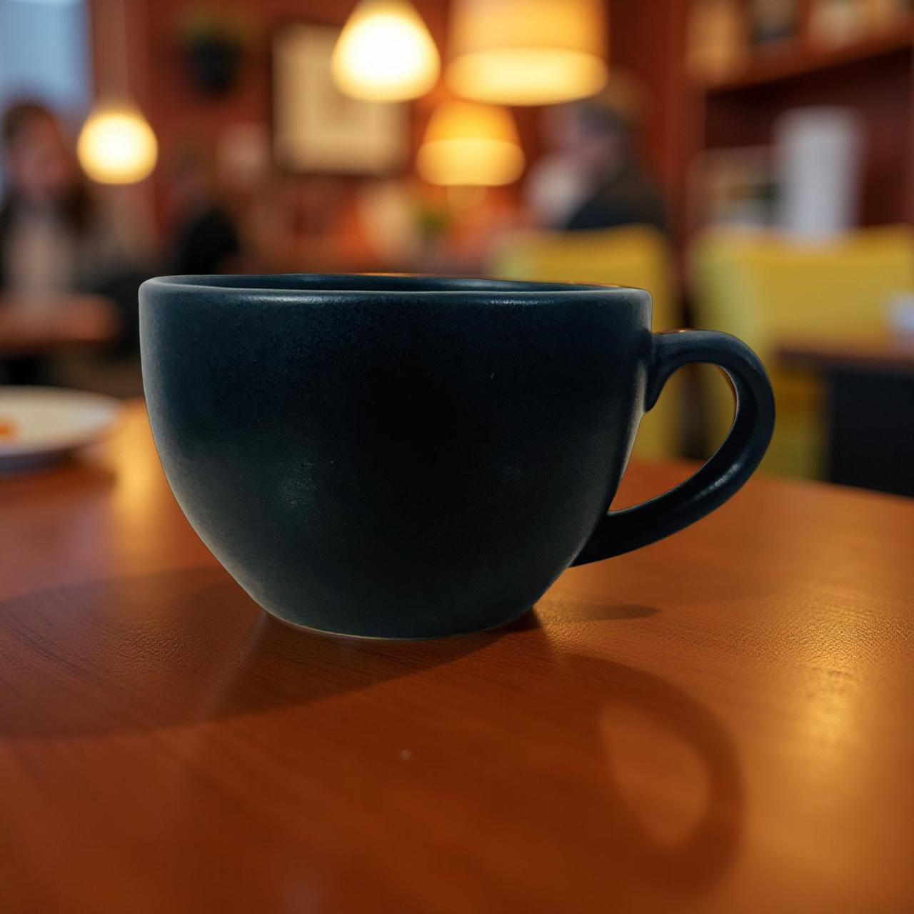 Black mug on a wooden table with a blurred cafe background