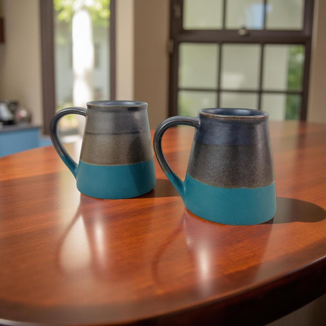 Two ceramic mugs with blue and brown design on a wooden table.