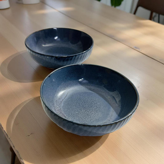 Two blue ceramic bowls on a wooden surface