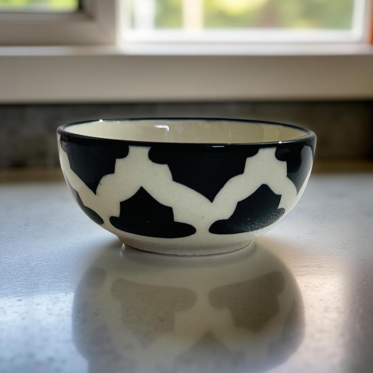 Ceramic bowl with black and white pattern on a reflective surface
