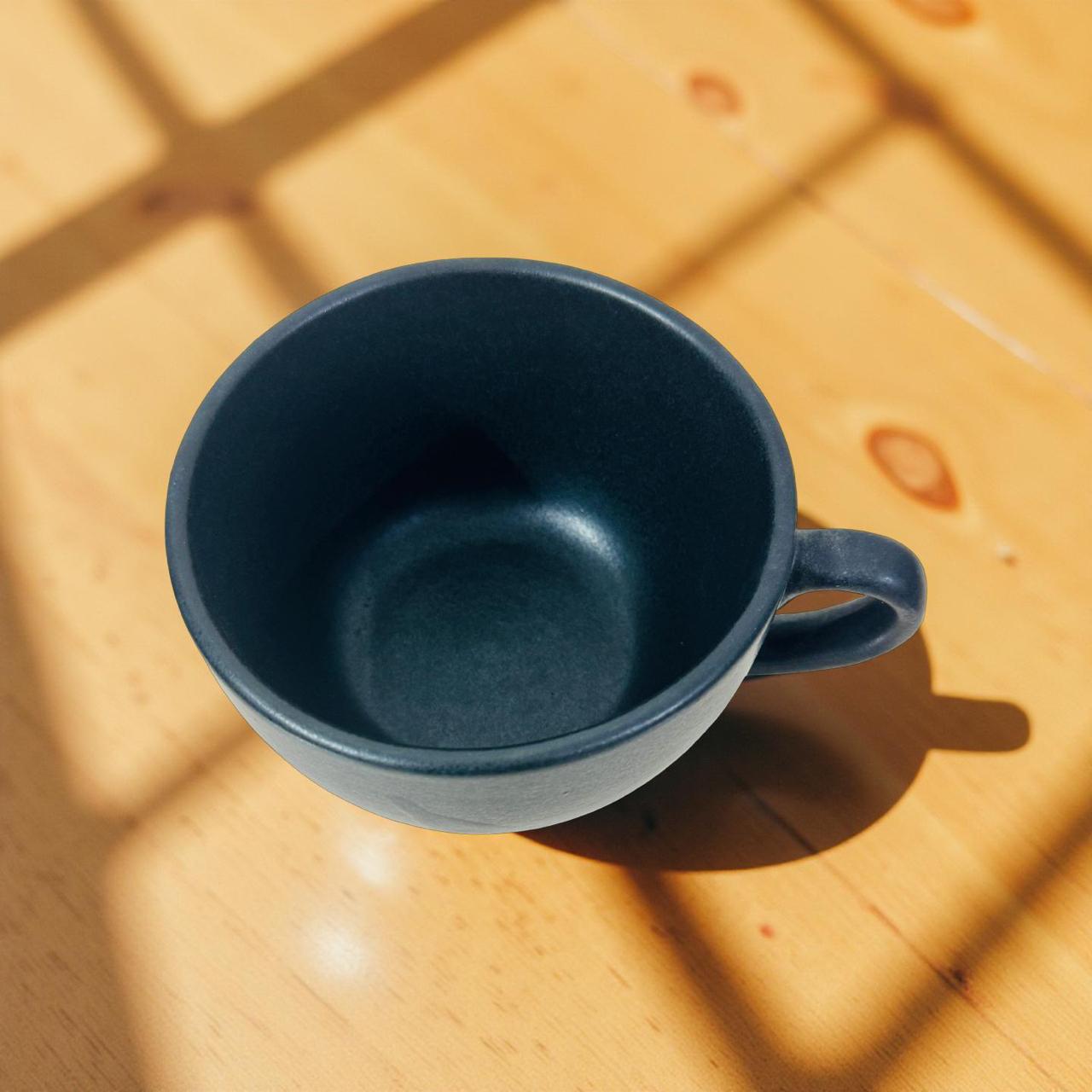 Blue mug on a wooden surface with sunlight casting shadows