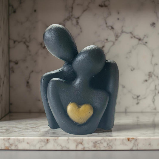 Decorative sculpture of two figures embracing with a heart on a marble surface