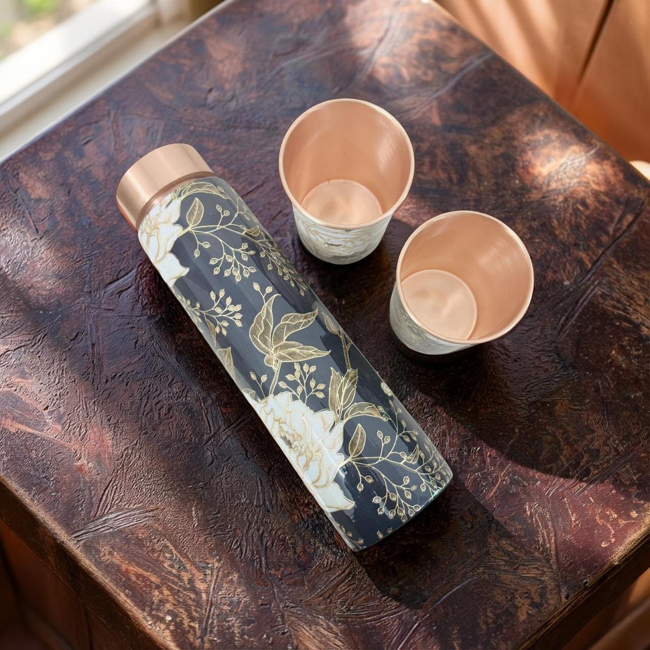 Floral-patterned water bottle and two ceramic cups on a textured surface