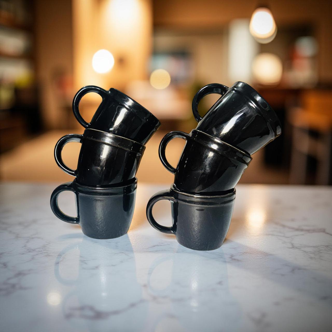 Stacks of black mugs on a marble countertop with a blurred background