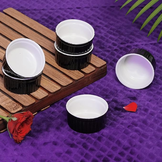 Black and white ceramic containers on a wooden tray with a purple background