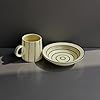 Ceramic mug and plate with concentric circle design on a gray background