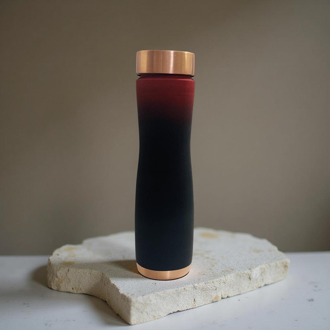 Black and red thermos with bronze cap on a stone surface