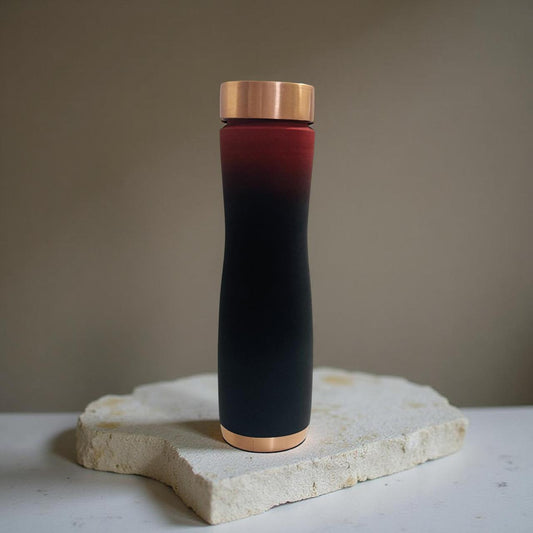 Black and red thermos with bronze cap on a stone surface