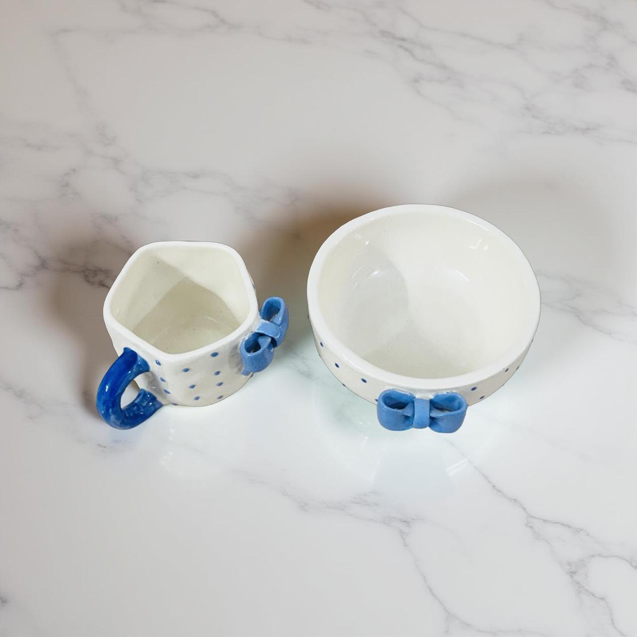 Two ceramic bowls with blue handles on a marble surface
