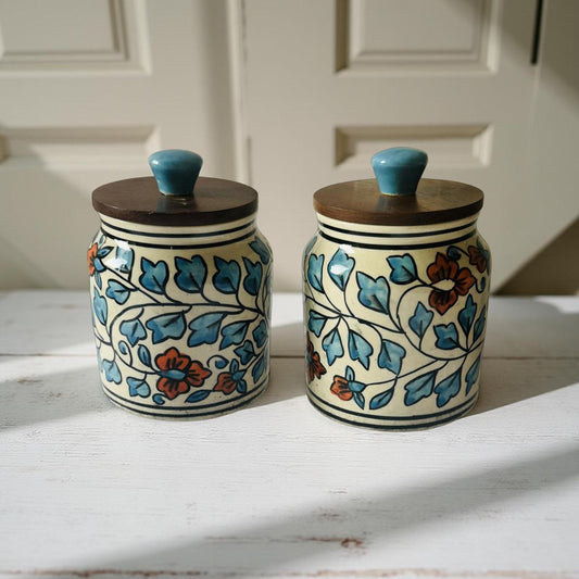 two beautiful handpainted ceramic jars placed on a white wooden countertop