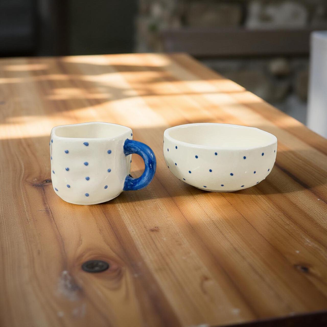 Ceramic mug and bowl with blue polka dots on a wooden table