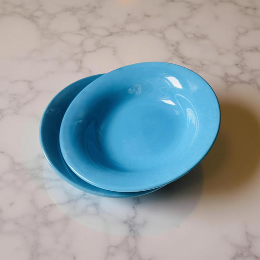 Two blue bowls stacked on a marble surface