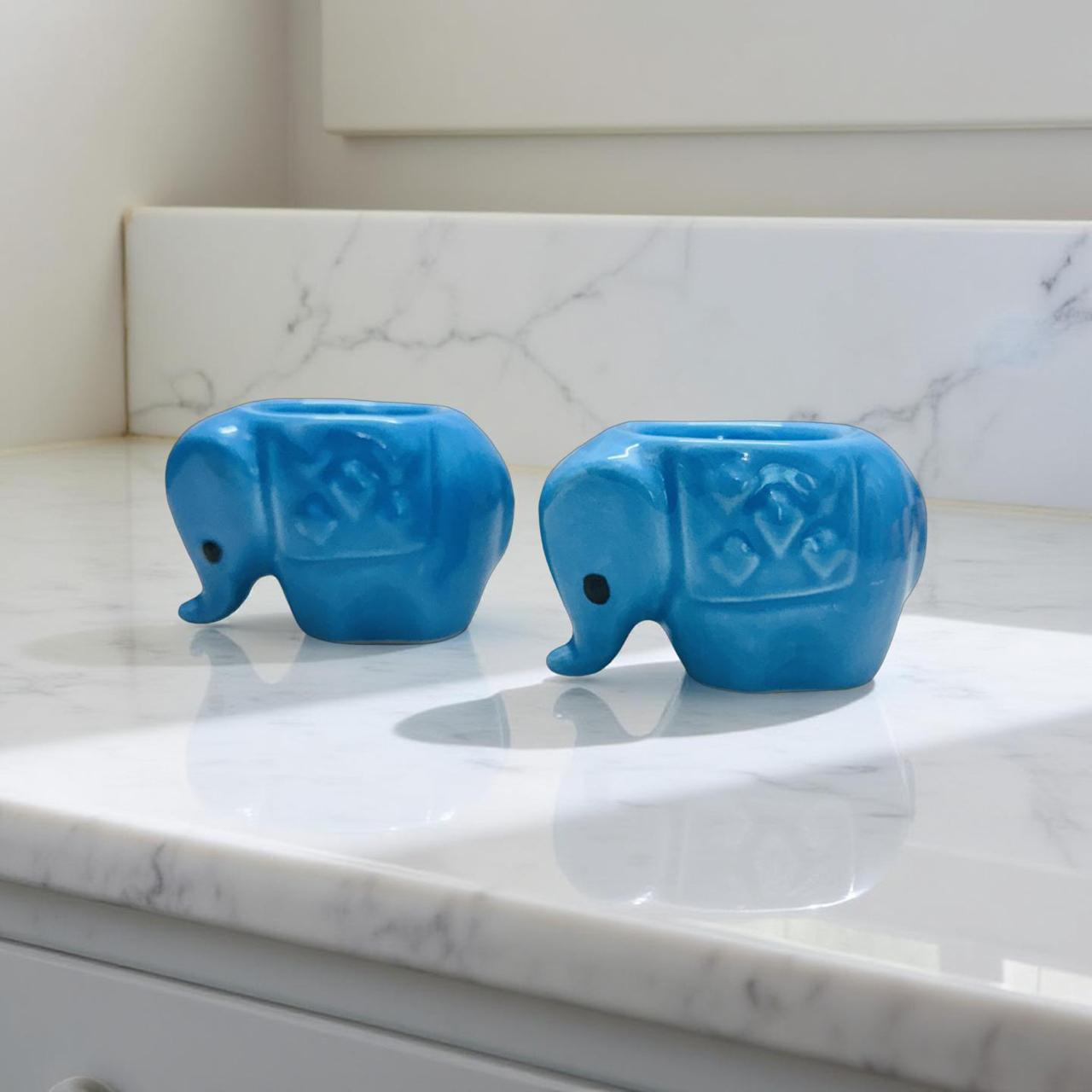 Two blue elephant-shaped objects on a marble countertop.