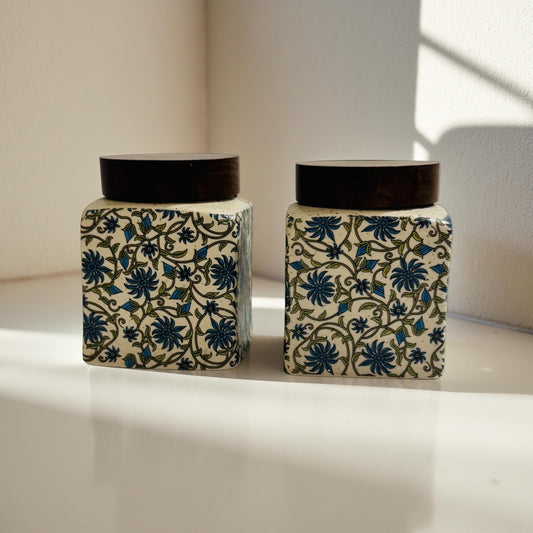 Two decorative jars with floral patterns on a light surface.