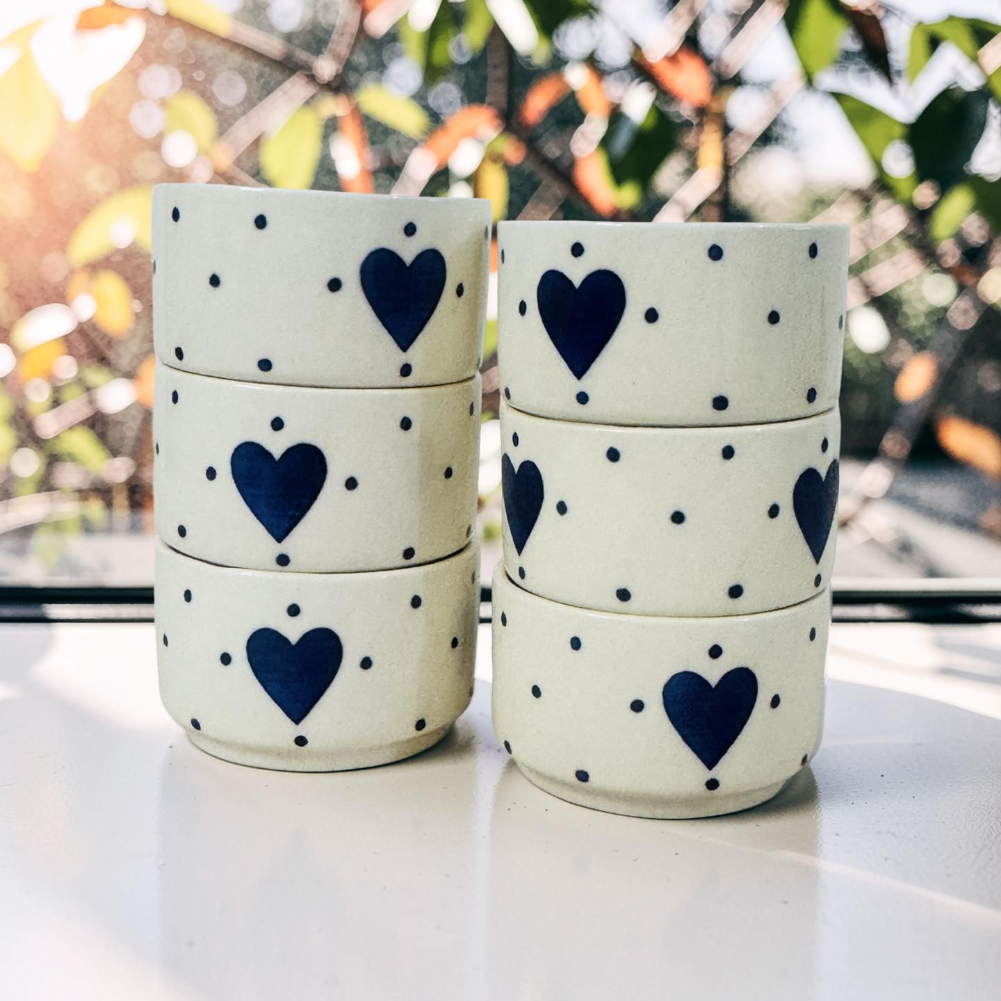 Two sets of ceramic containers with blue heart designs on a white surface.
