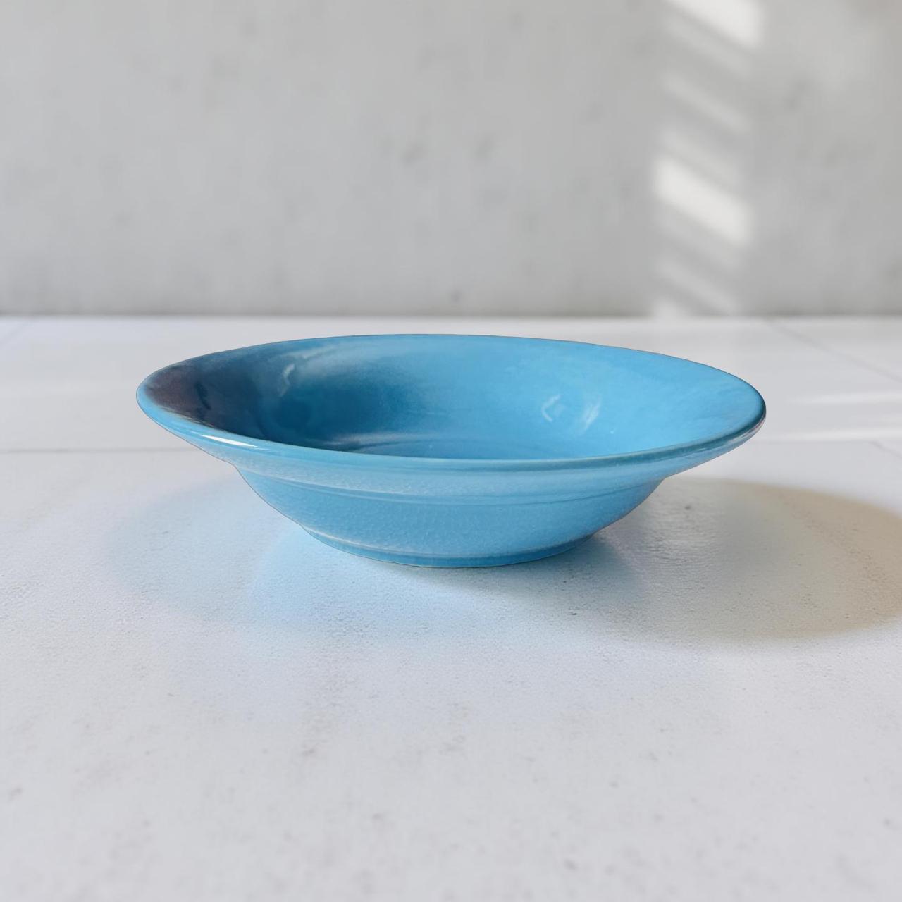 Blue ceramic bowl on a white surface with a light gray background