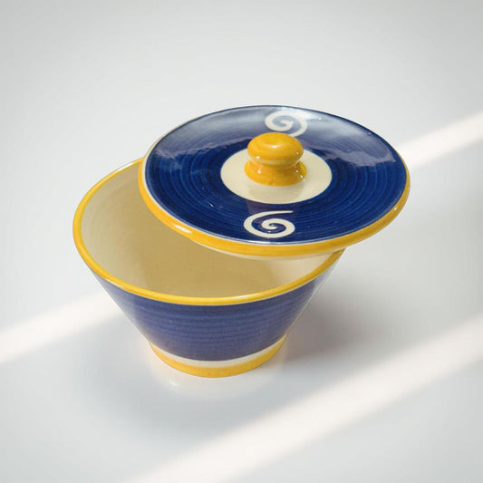 Ceramic bowl with blue lid featuring a spiral design on a white background