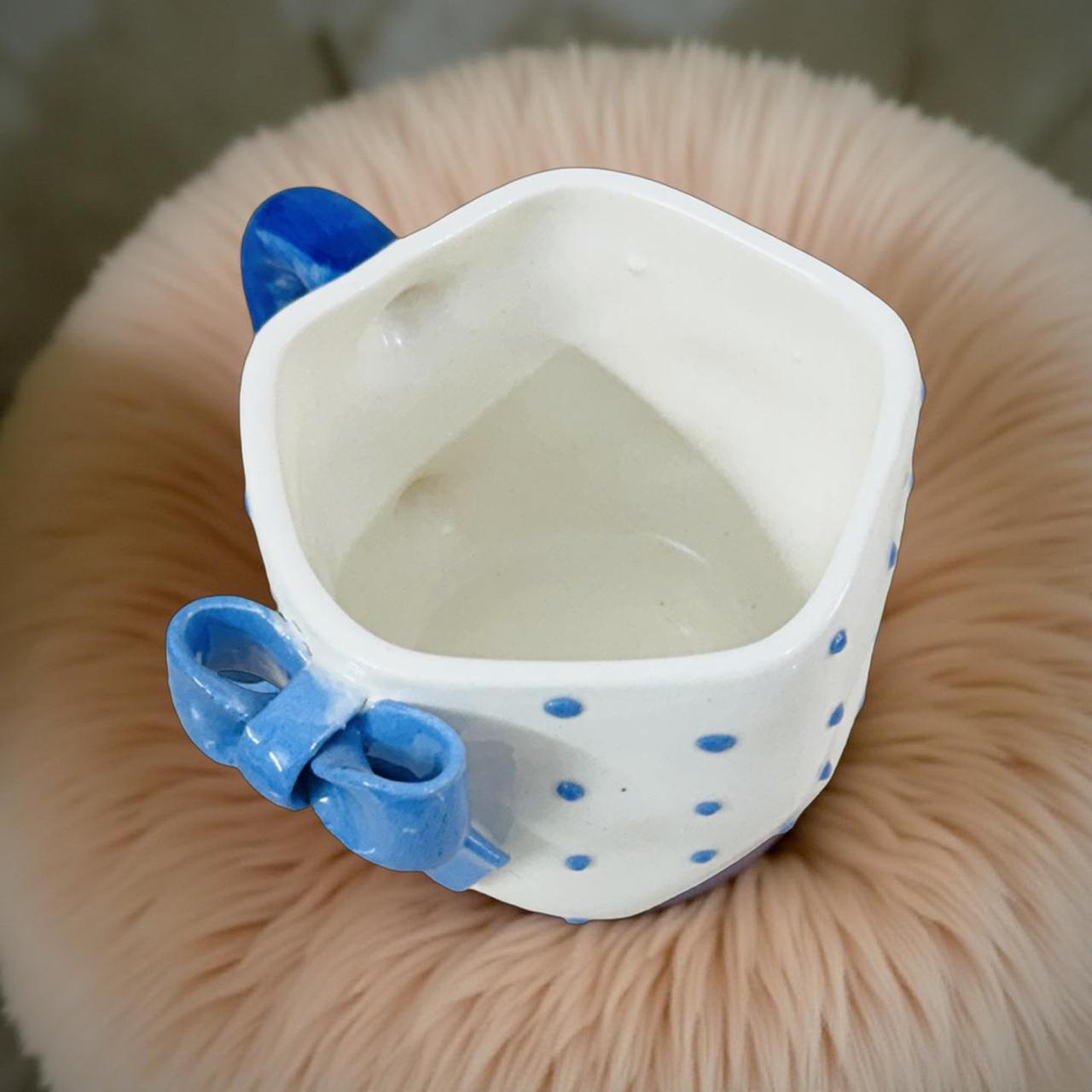 White pet water bowl with blue handles on a fluffy pink cushion