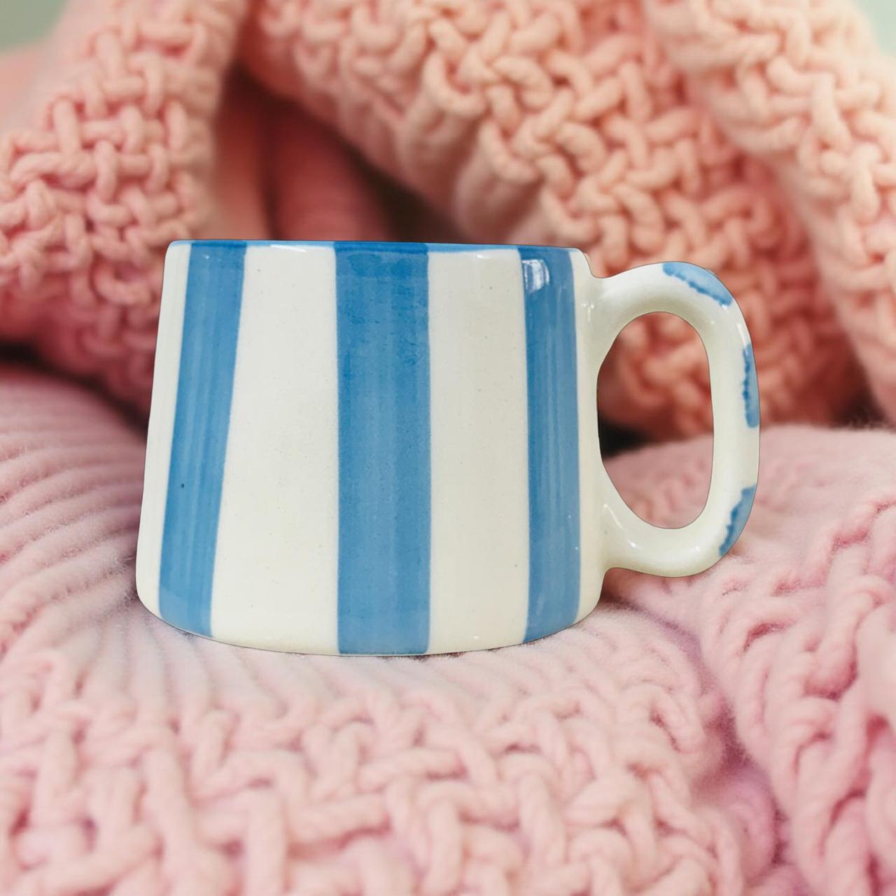 Blue and white striped mug on pink knitted fabric