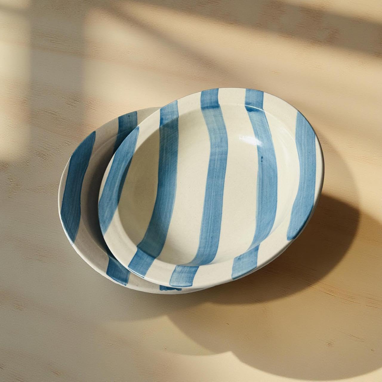 Oval ceramic plate with blue and white stripes on a wooden surface