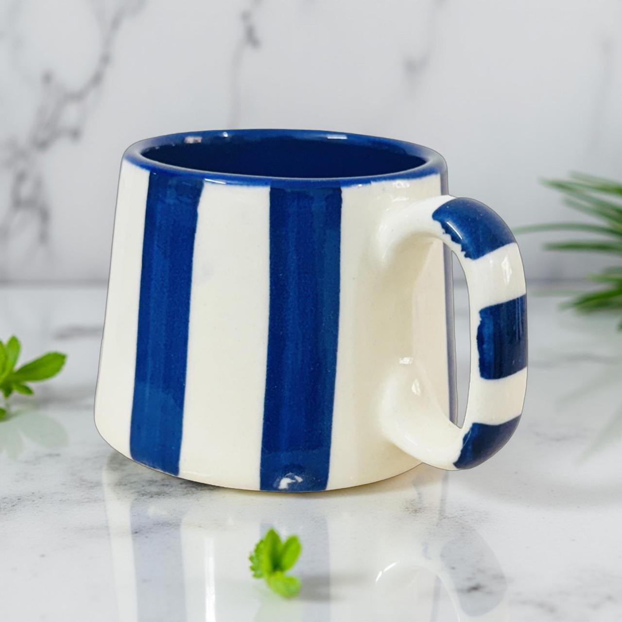 Blue and white striped mug on a marble surface with greenery.