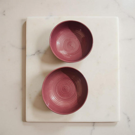 Two pink ceramic bowls on a marble surface