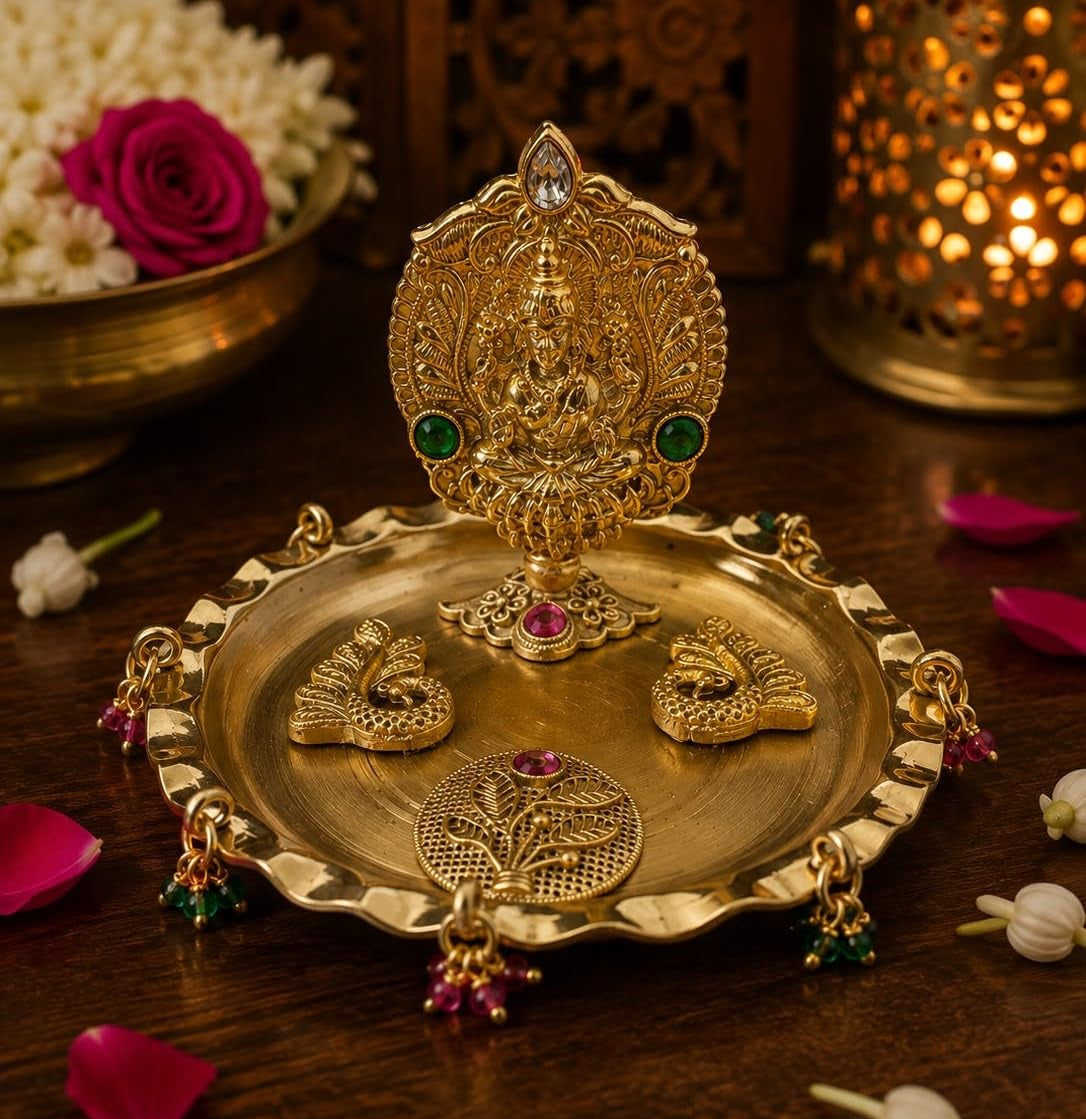 An ornate gold-toned Diwali oil lamp and matching decorative tray set on a dark wooden surface, with flowers and a glowing lantern in the background.