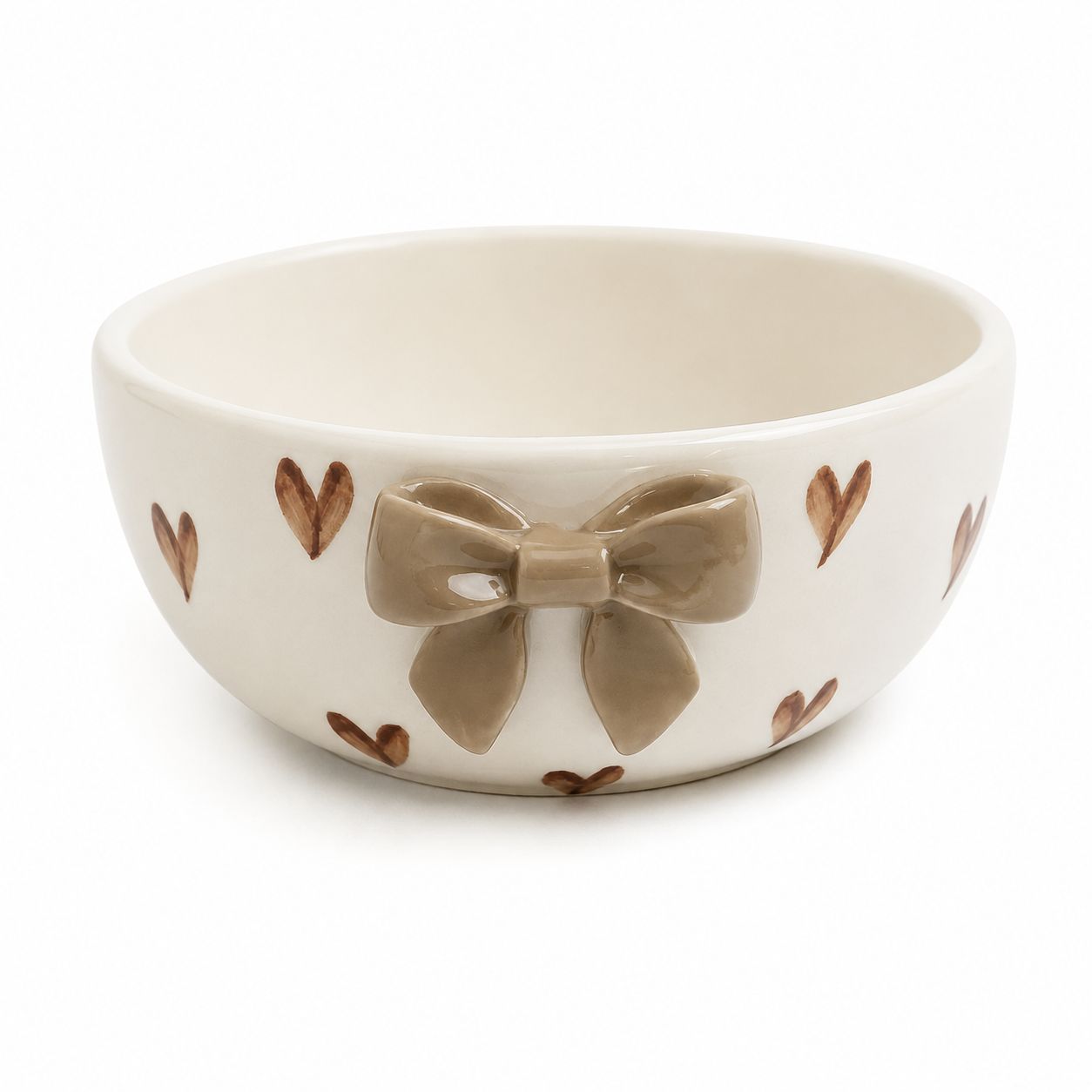 An off-white ceramic bowl decorated with a large 3D taupe bow on the front and small brown hearts around the exterior, set against a plain white background.