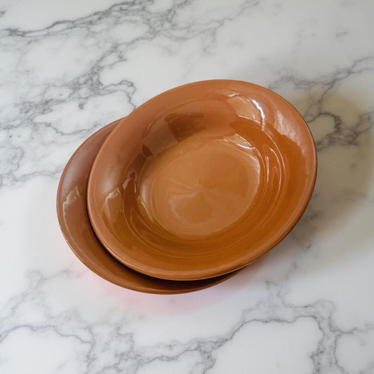 Two terracotta bowls stacked on a marble surface