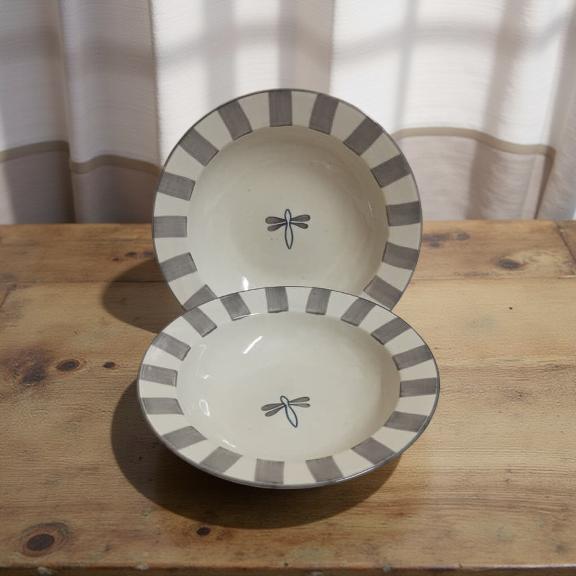 Two ceramic bowls with striped rims on a wooden surface