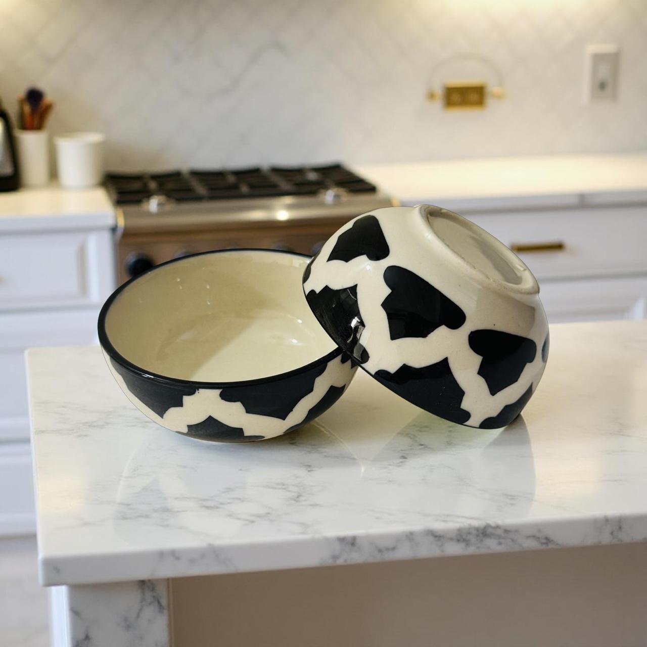 Cow print ceramic bowls on a marble countertop in a kitchen.