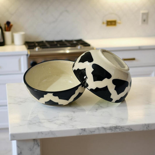 Cow print ceramic bowls on a marble countertop in a kitchen.