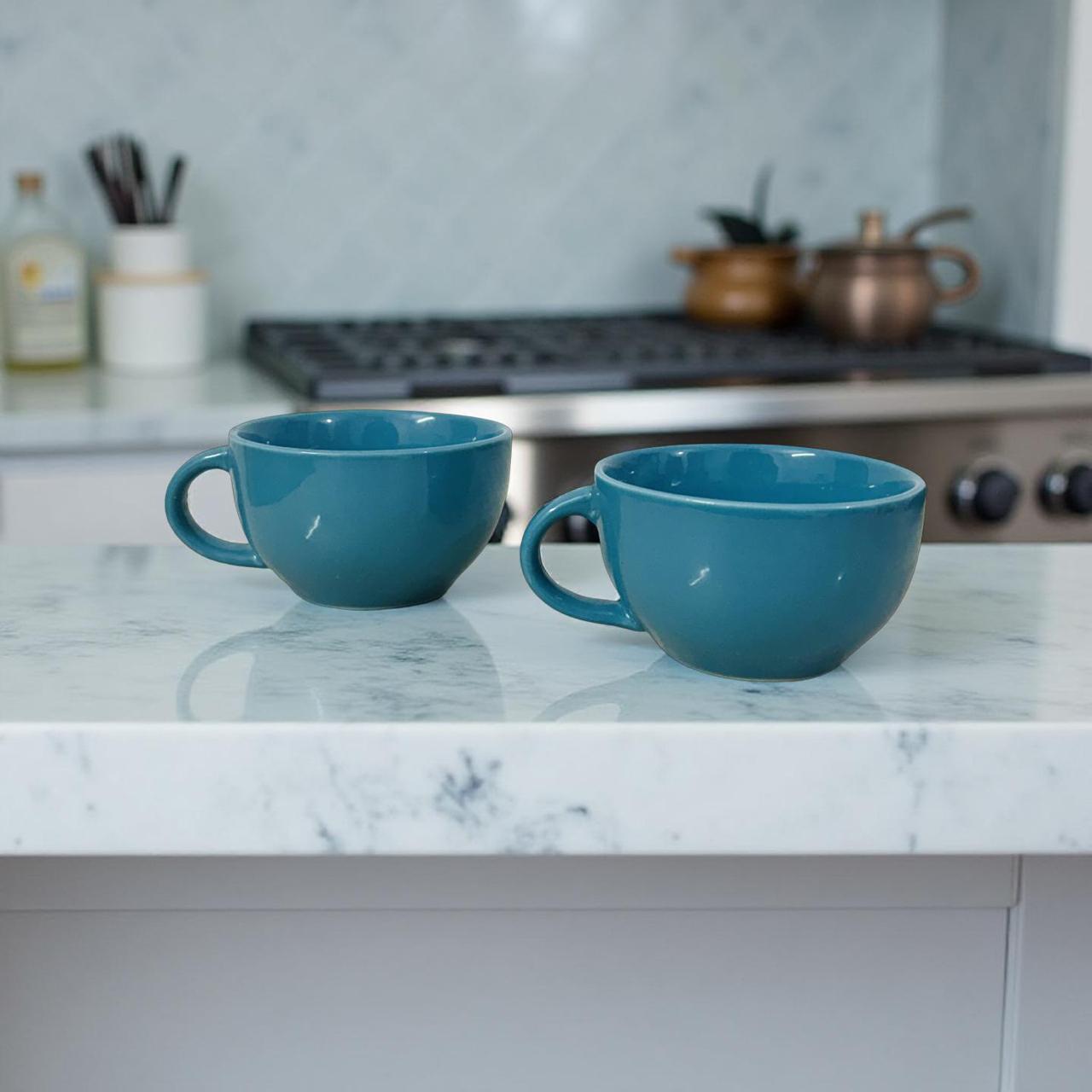 two big blue ceramic coffee mugs are kept on a kitchen platform