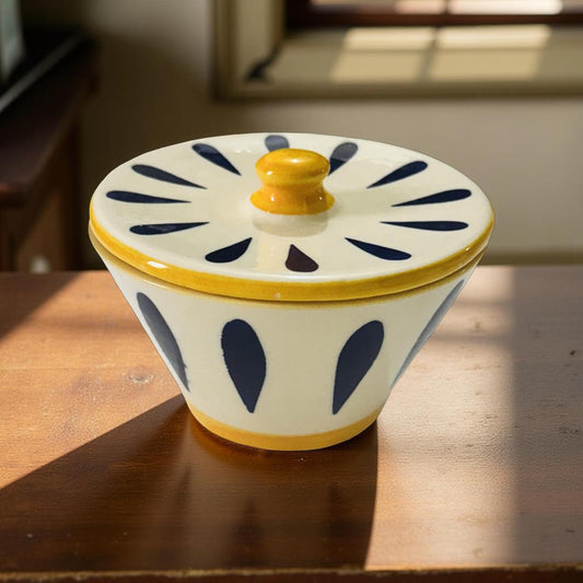 Ceramic container with blue patterns and yellow accents on a wooden surface