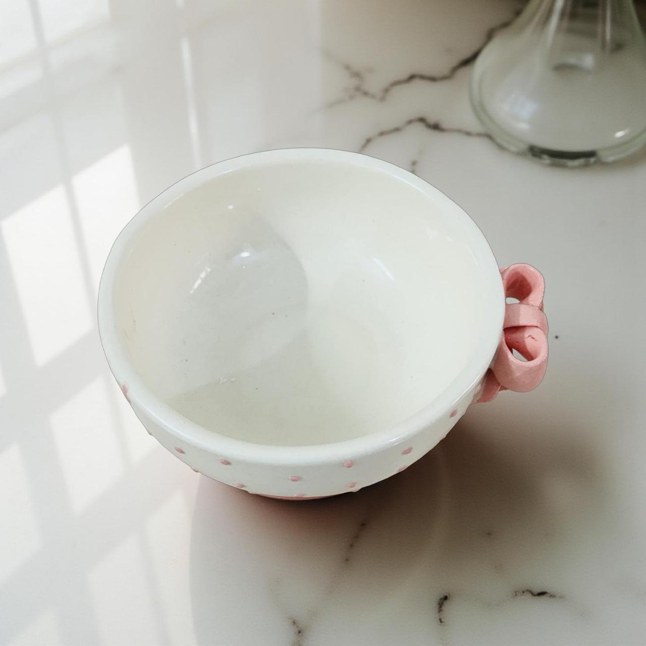 White ceramic bowl with pink handle on a marble surface
