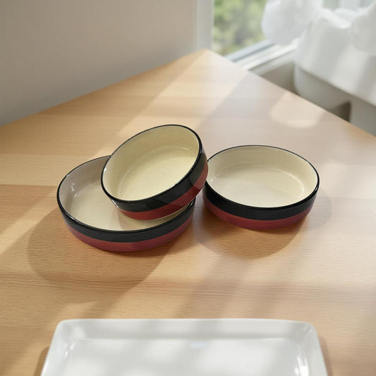 Set of ceramic bowls with red and black rim on a wooden table