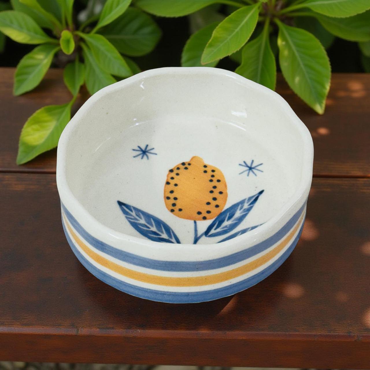 Ceramic bowl with lemon design on a wooden surface with green leaves in the background