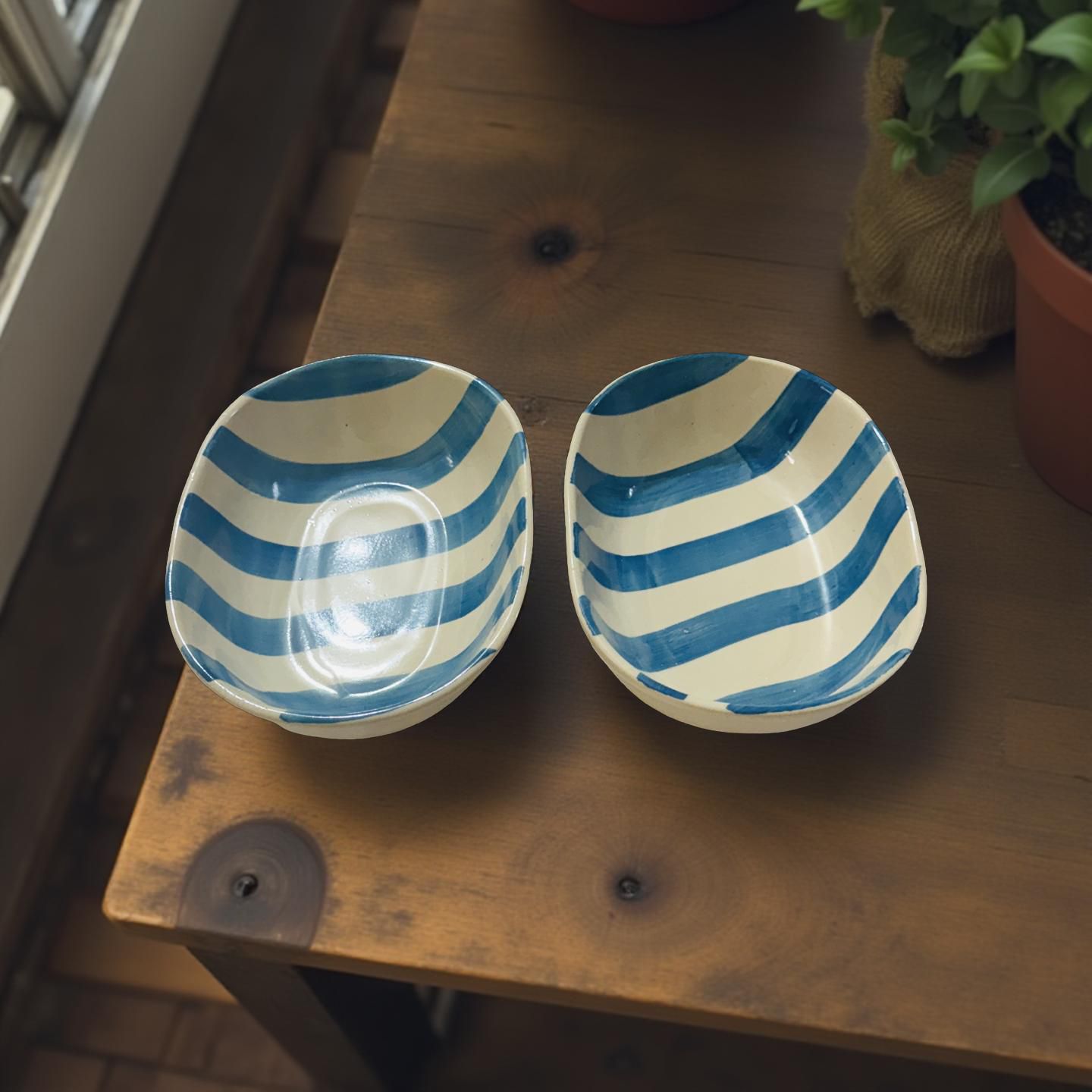 Two ceramic bowls with blue and white striped patterns on a wooden surface.